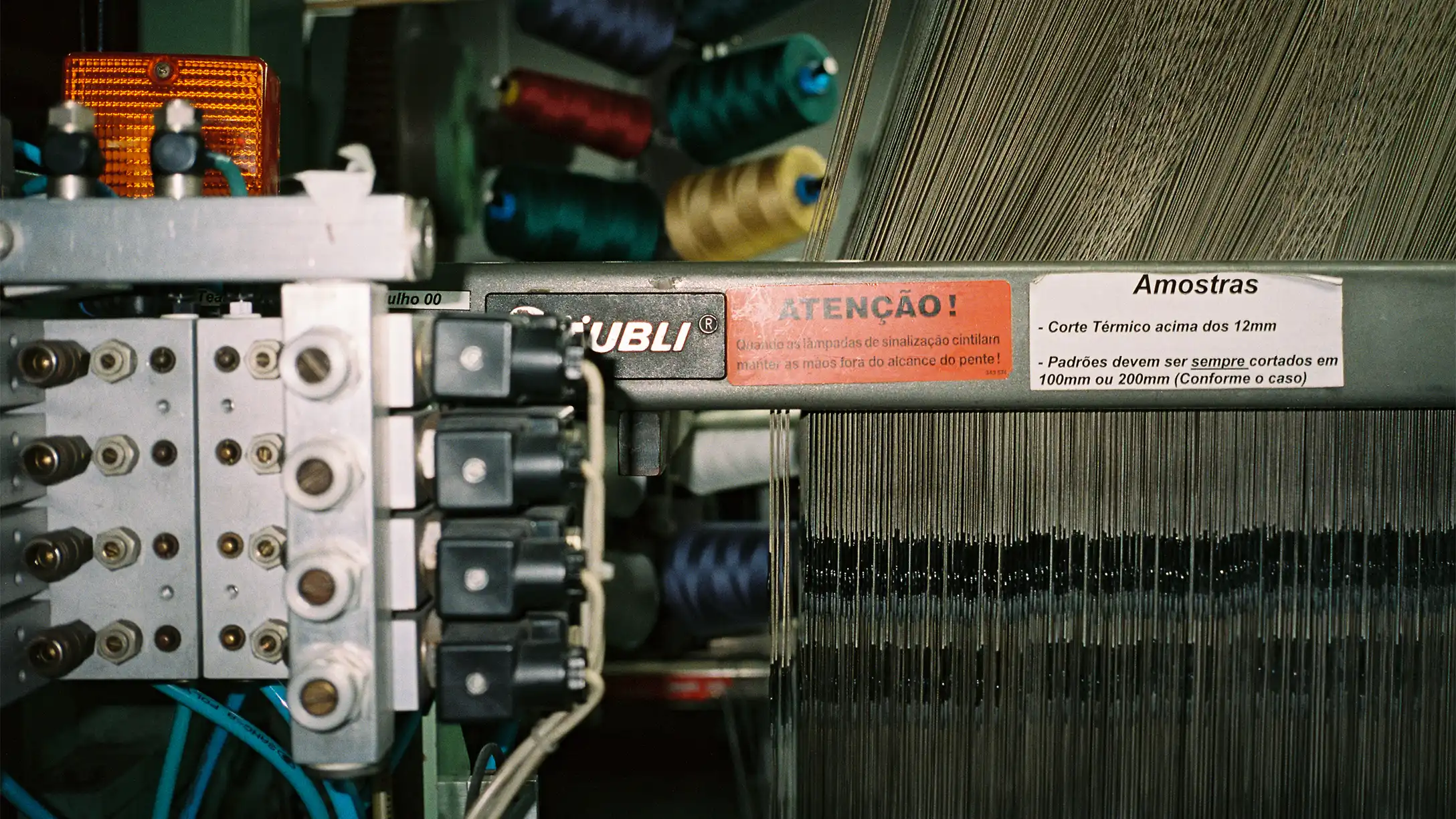 Close-up of a textile knitting machine with coloured yarn cones in northern Portugal