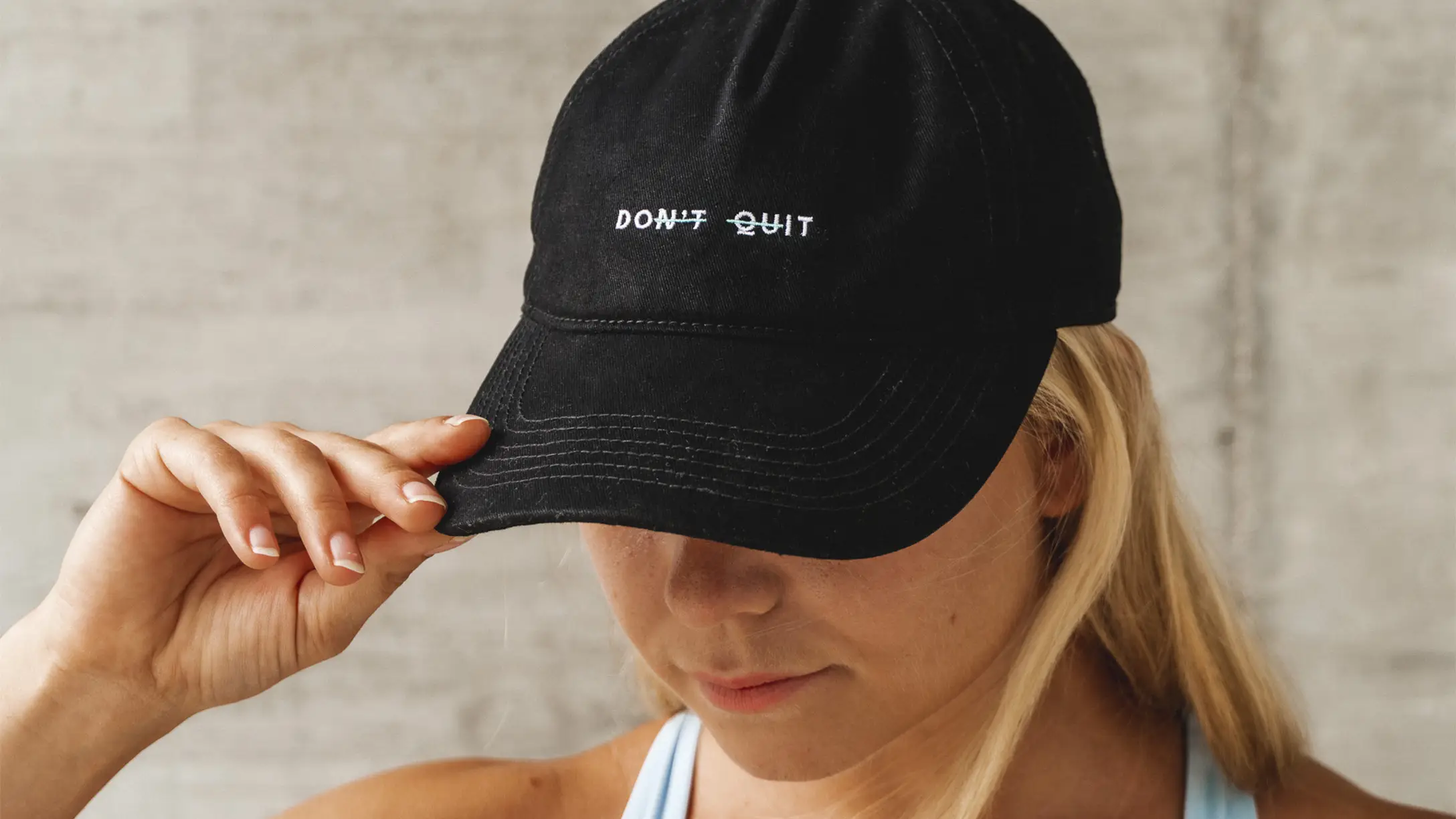 black cap with an embroidered don't quit message, worn in the everyday